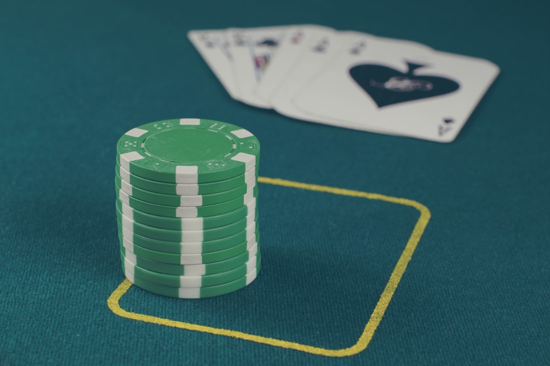 Chip kasino warna hijau bertumpuk di atas meja permainan